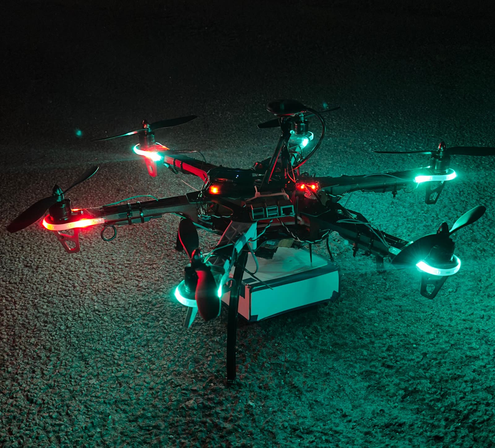 Murphy Mark VI hexacopter at night, navigation lights lit, payload bay slung underneath